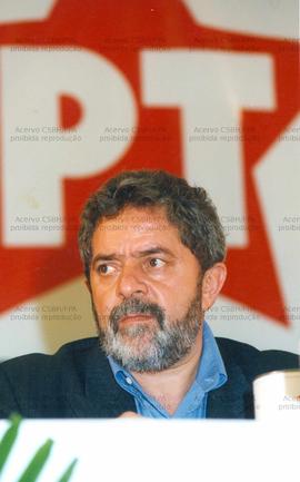 Lula em evento não identificado com bandeira do PT ao fundo (Local desconhecido, 1999). / Crédito: Roberto Parizotti