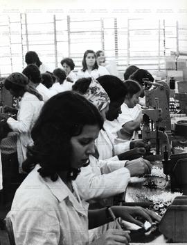 Mulheres trabalham em linha de montagem de peças (Local desconhecido, Data desconhecida). / Crédito: Silvestre P. Silva.