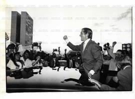 Fernando Collor de Mello com os punhos cerrados ao lado de manifestantes e fotógrafos (Brasília-DF, 28 jun. 1991).  / Crédito: Leila Marques/Agência Folha.
