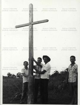 Trabalhadores rurais seguram cruz de madeira (Local desconhecido, Data desconhecida).  / Crédito: Autoria desconhecida.