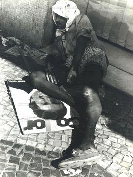 Retrato de morador de rua ao lado de placa de propaganda de Fernando Collor [nas eleições de 1989...