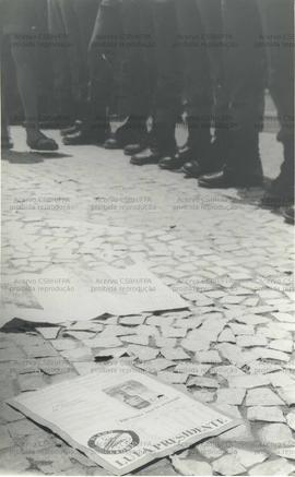 Material de campanha da candidatura &quot;Lula Presidente&quot; (PT) no chão próximo a uma barreira de soldados, no contexto da camanha eleitoral de 1989 (Vitória da Conquista-BA, 1989). / Crédito: J C d&#039;Almeida .