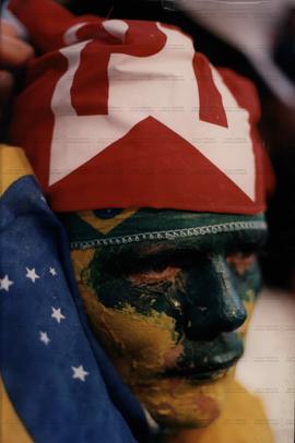 Rosto pintado com a bandeira do Brasil e com a cabeça coberta pela bandeira do PT (Local desconhecido, Data desconhecida). / Crédito: Autoria desconhecida