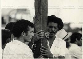 Trabalhadores rurais seguram cruz de madeira (Local desconhecido, Data desconhecida).  / Crédito:...
